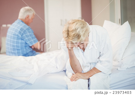 Tensed senior couple sitting in bedroom Tensed senior couple sitting in bedroom 23973403
