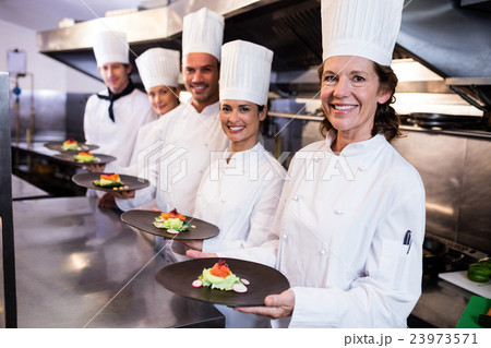 Happy chefs presenting their food plates 23973571