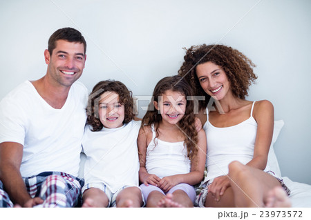 Portrait of a family sitting together on bed 23973572