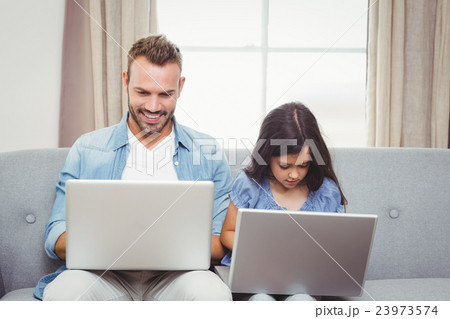 Father and daughter using laptop at home Father and daughter using laptop at home 23973574