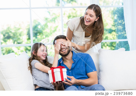 Man surprised with gift in sofa Man surprised with gift in sofa 23973680