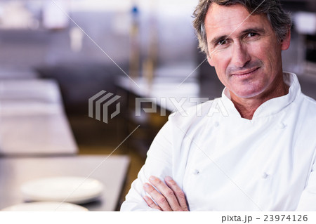 Smiling chef with hands crossed in the kitchen Smiling chef with hands crossed in the kitchen 23974126