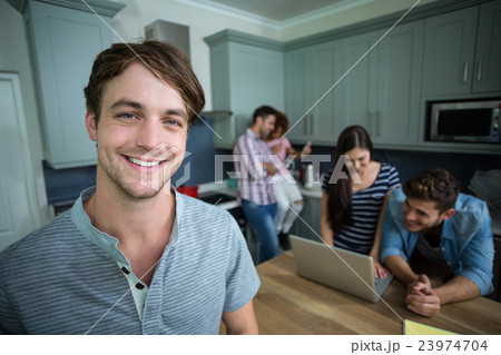 Portrait of happy man with friends in background at home 23974704