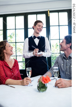 Young waitress laughing while taking an order from a couple 23974750