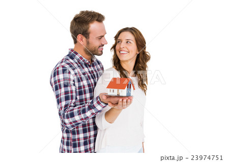 Happy young couple holding model house Happy young couple holding model house 23974751