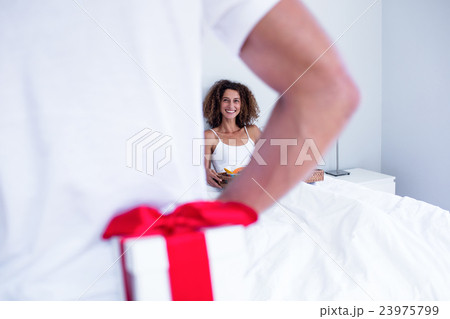 Man hiding gift behind his back for wife 23975799