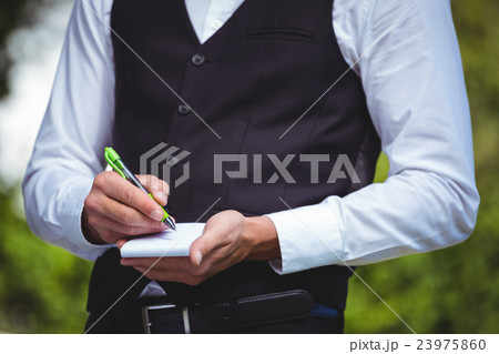 Handsome waiter writing the order 23975860