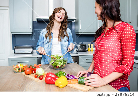 Smiling female friends preparing salad 23976514