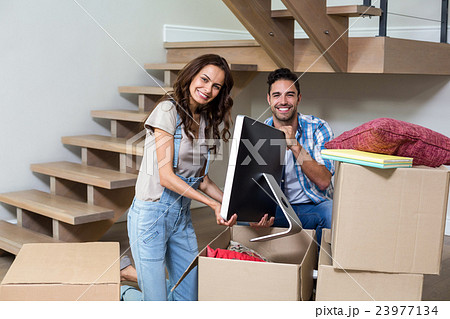 Portrait of happy couple unpacking computer from cardboard box Portrait of happy couple unpacking computer from cardboard box 23977134