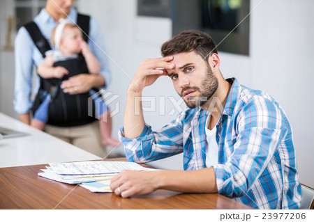 Tensed man with wife and baby in background Tensed man with wife and baby in background 23977206