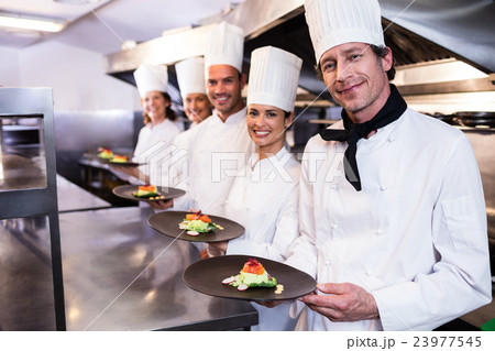 Happy chefs presenting their food plates 23977545