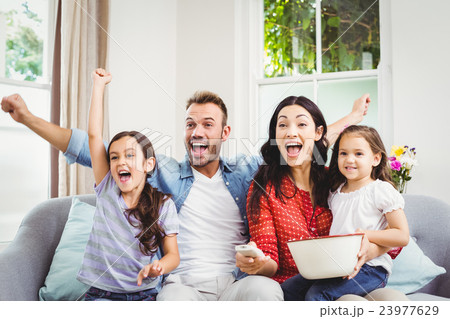 Family cheering while watching TV at home Family cheering while watching TV at home 23977629