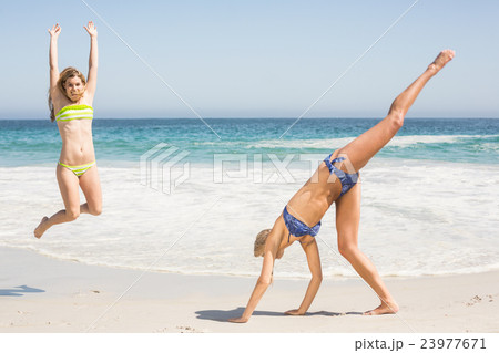 Two women jumping on the beach 23977671