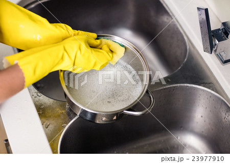 Woman wearing gloves washing utensils Woman wearing gloves washing utensils 23977910