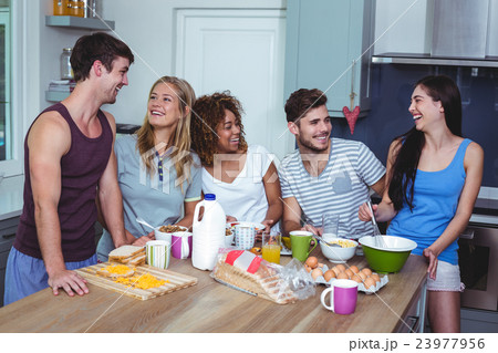 Smiling friends discussing at breakfast table 23977956