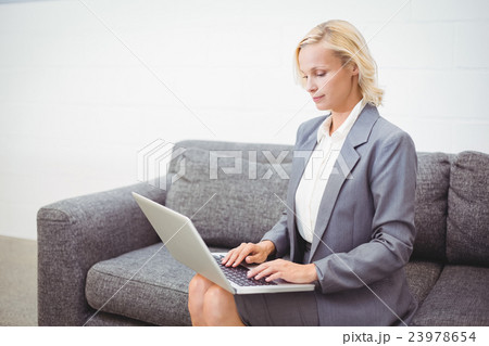 Bussinesswoman working on laptop while sitting on sofa 23978654