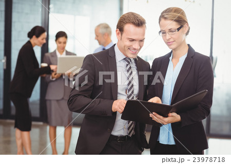 Businessman and businesswoman looking at file 23978718