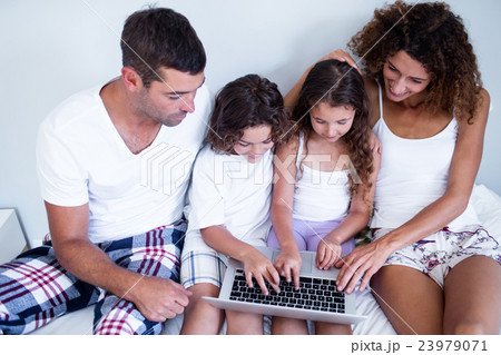 Family using laptop together on bed 23979071