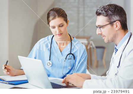 Male doctor with colleague working on laptop 23979491