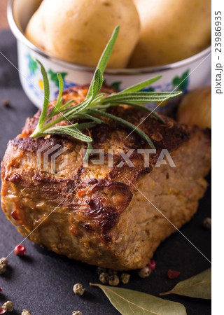 Baked piece of pork meat on black slate stone Baked piece of pork meat on black slate stone 23986935