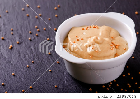Mustard in white bowl on black slate stone 23987058