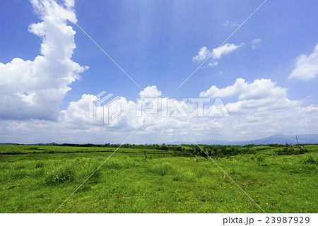 阿蘇の高原と晴天の青空から降り注ぐ光芒爽やかな背景素材の写真素材