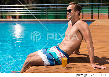 Pleasant cheerful man sitting near swimming pool Pleasant cheerful man sitting near swimming pool 24008474