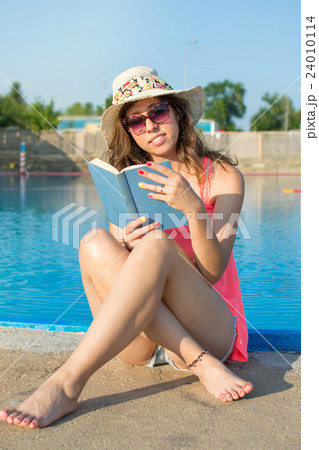 Girl reading a book by the pool. 24010114