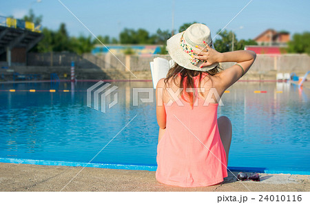 Girl reading a book by the pool 24010116