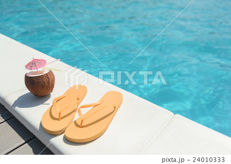 Colored slippers and beverage near water 24010333