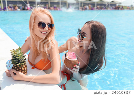 Happy young women drinking cocktails in pool 24010337