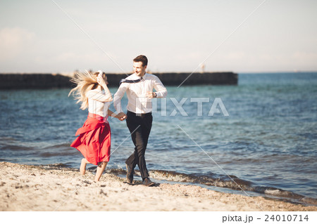 Young happy couple walking on beach smiling Young happy couple walking on beach smiling 24010714