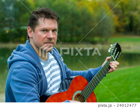 Mature bearded man playing red guitar Mature bearded man playing red guitar 24012477