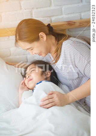 Asian mother awaking her daughter on the bed 24032523