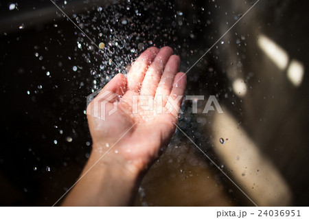 Human hand in sunlight under falling water. 24036951