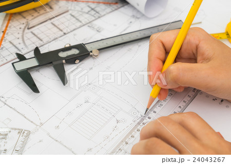 Hand over Construction plans with yellow helmet and drawing tools on blueprints . Hand over Construction plans with yellow helmet and drawing tools on blueprints . 24043267