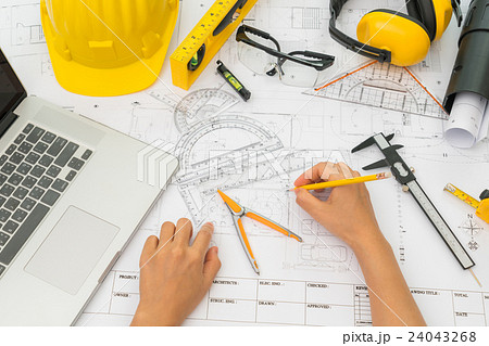 Hand over Construction plans with yellow helmet and drawing tools on blueprints . Hand over Construction plans with yellow helmet and drawing tools on blueprints . 24043268