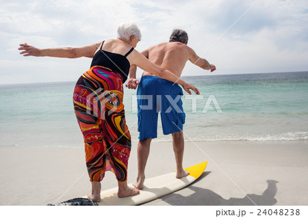 Senior couple surfing on beach Senior couple surfing on beach 24048238