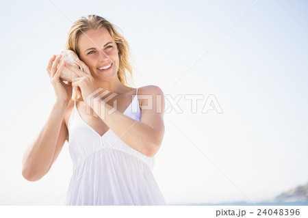Woman listening into a seashell 24048396
