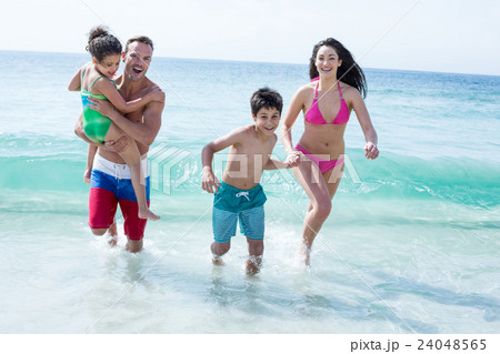 Father and mother running with children at beach Father and mother running with children at beach 24048565