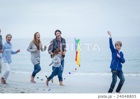 Cheerful multi-generation family running at sea shore Cheerful multi-generation family running at sea shore 24048805