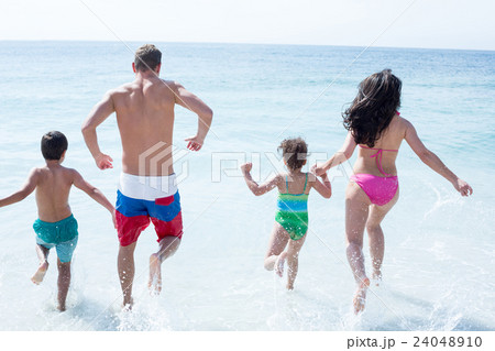 Rear view of family running at beach  24048910
