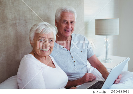 Happy retired couple holding laptop  24048945