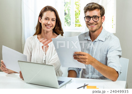 Portrait of male and female colleagues discussing document at office 24049935