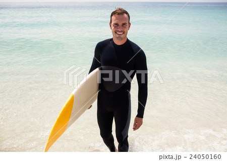 Happy surfer holding a surfboard on the beach Happy surfer holding a surfboard on the beach 24050160