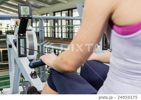 Woman exercising on rowing machine 24050175