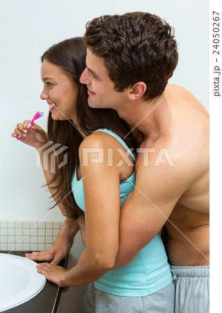 Couple hugging while brushing teeth Couple hugging while brushing teeth 24050267