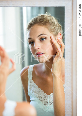 Woman checking her skin in bathroom 24050366