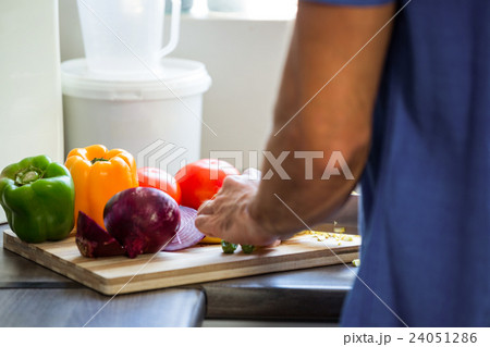 Man chopping vegetables at kitchen counter 24051286