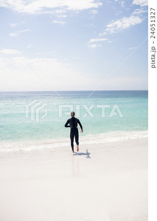 Surfer running towards sea with a surfboard Surfer running towards sea with a surfboard 24051327